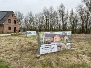 Bauschild „Ihr neues Traumhaus ist in Arbeit“ auf dem Grundstück
