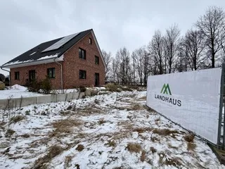 Verschneites Grundstück mit Landhaus-Banner